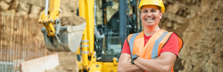 Portrit of a reliable excavating worker,looking at the camera with his arms crossed. At the background is the excavator the he drives.