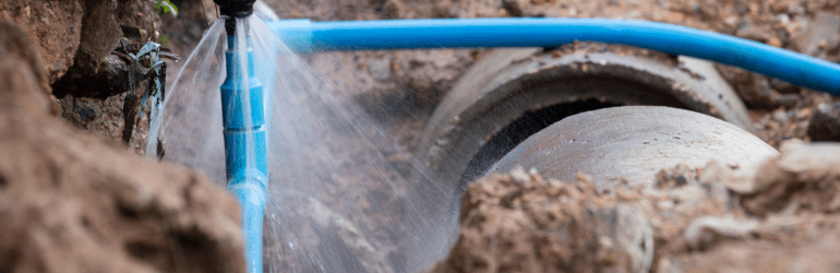 Water pipe break .Exposing a burst water main, focused on the spraying water and the pipe